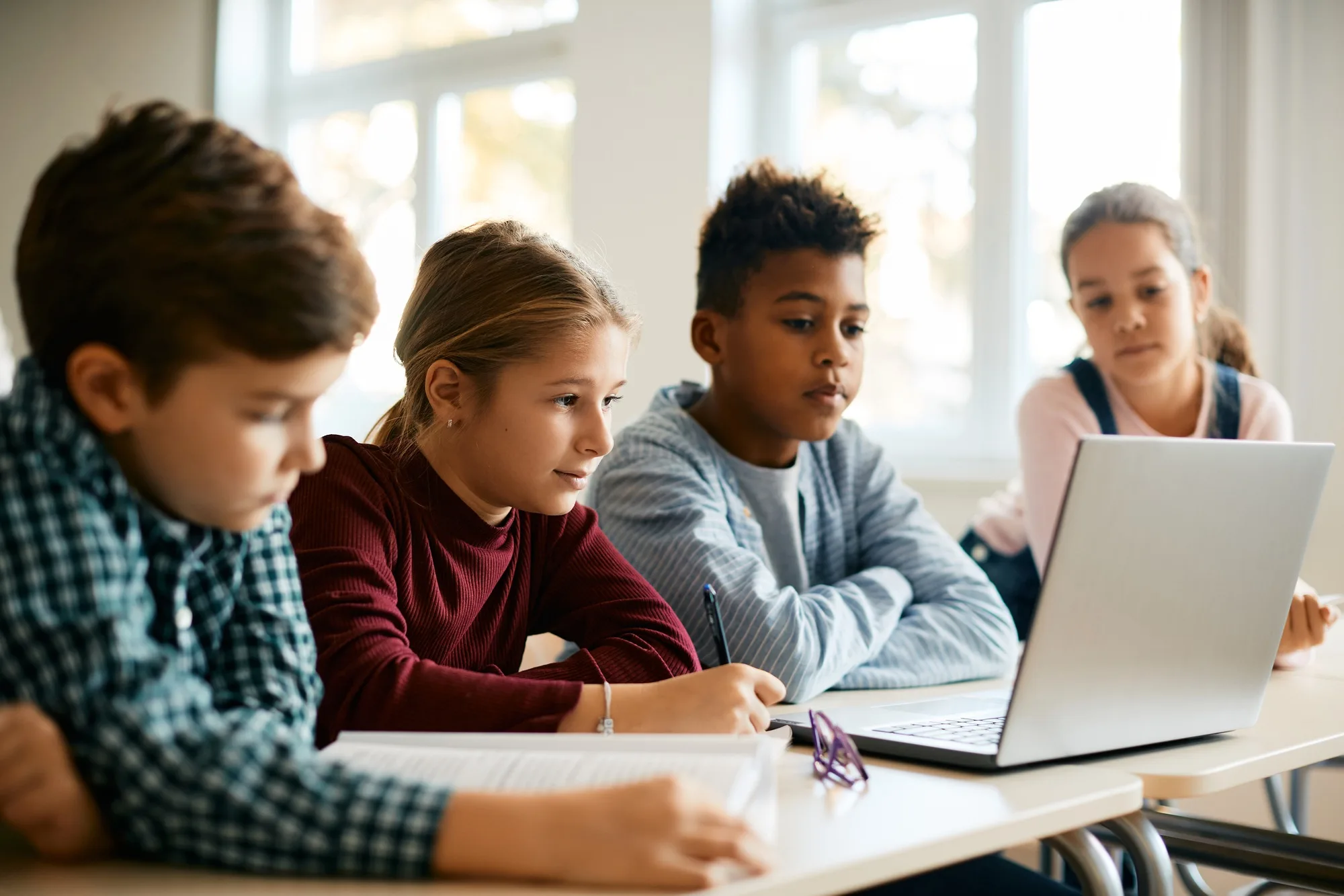 Group of elementary school classmates e-learning on laptop in the classroom.
